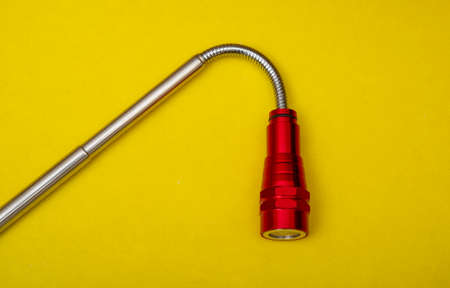 Folding portable torch light on yellow background.