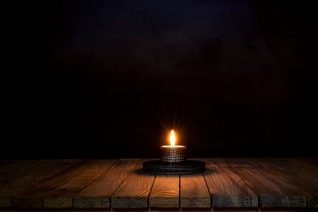 Candle light spreading on wooden table surface.の写真素材
