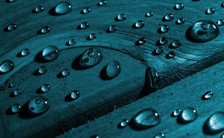 Closeup view of rain water drops on blue wooden sheet.