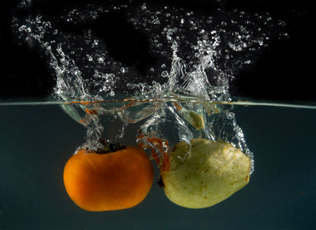 Fruits going into water with splash all around - fresh eating concept.の写真素材