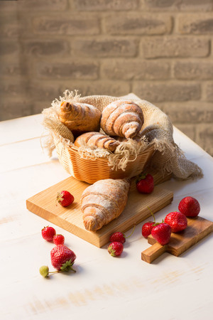 Delicious breakfast with fresh croissants and fresh berries on a wooden backgroundの写真素材