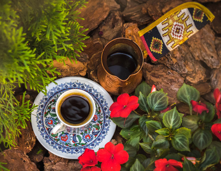 A coffee cup with saucer and jezva stand among the bark, flowers and branches of cypress. Top Viewの写真素材