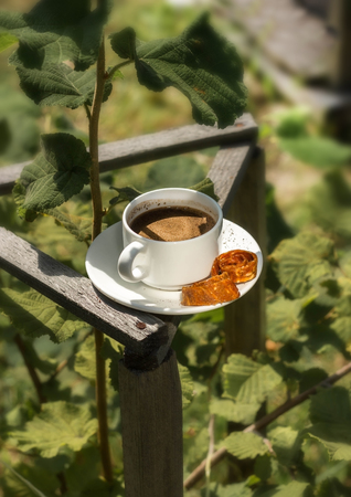 A cup of coffee in the garden on the background of leavesの写真素材