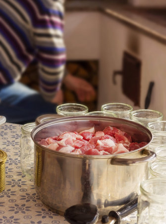 Chef prepares a meat dish. On the table is a large saucepan with chunks of chopped meatの写真素材