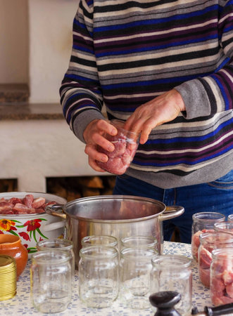 Chef standing at a table in the kitchen, cooking. Traditional cuisine. Pieces of meat in a glass jarの写真素材