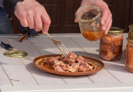 A man puts slices of stew on a clay plate. Dinner. Close view. Daylight.の写真素材