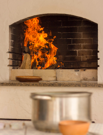 BBQ with a burning fire on the background of a table with pots and household utensilsの写真素材
