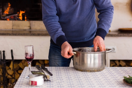 Man is mixing the minced meat in a metal pan against the backdrop of a fire in the barbecue. Photo setの写真素材