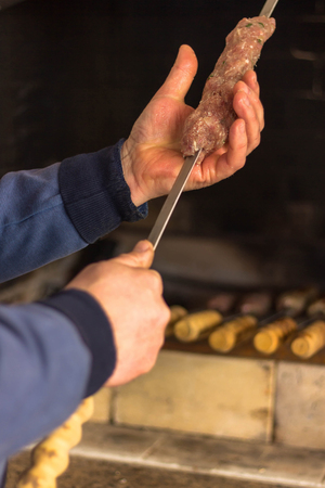 Man is stringing meat on a skewer. Cook makes a shish kebab for a summer party. Open fire.の写真素材