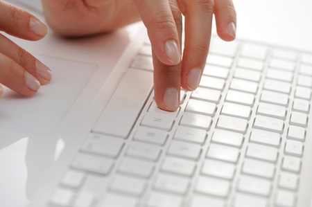 Female hands typing on a white computer keyboard