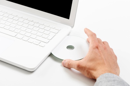 Businessman inserting a cd on white laptopの写真素材