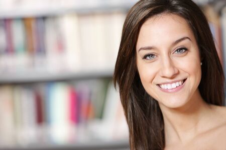 portrait of beautiful young woman standing in libraryの写真素材
