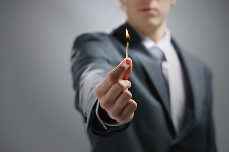 Business man hand holding a burning matchの写真素材