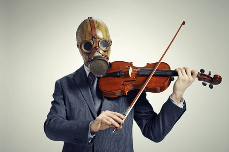 businessman with gas mask, plays the violinの写真素材