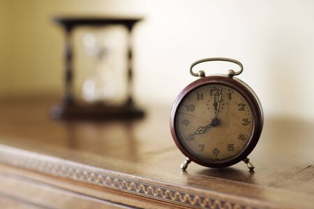 old alarm clock with hourglass on background, copy space
