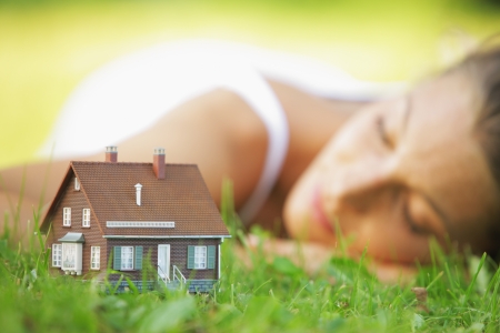Young woman on a lawn dreaming of her new homeの写真素材