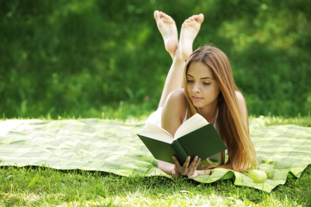 Closeup of a beautiful young woman reading book at parkの写真素材