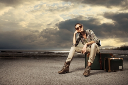 Beautiful young woman photographer sitting on a suitcase の写真素材