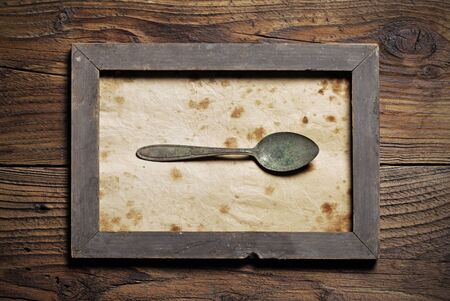 Metal spoon framed on old wood backgroundの写真素材