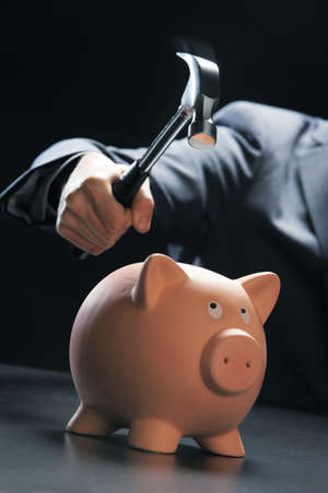 Hammer about to smash piggy bank, focus on hammer headの写真素材