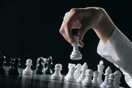 Female hand moving the queen in a chess game.の写真素材