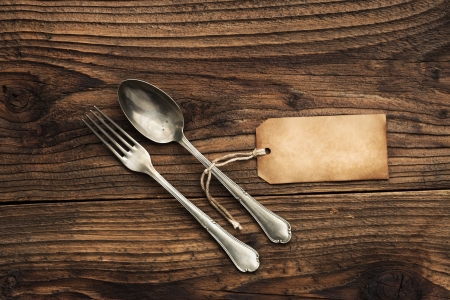 Old fork and spoon with paper label on wooden backgroundの写真素材