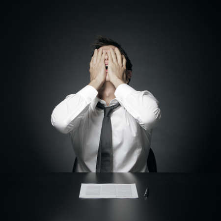 portrait of desperate office manager  covering his face with both hands