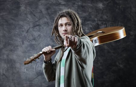 Young man with his guitars pointing at viewer