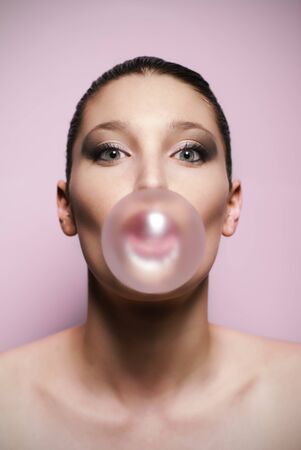 Beautiful woman blowing a big bubble gum bubbleの写真素材