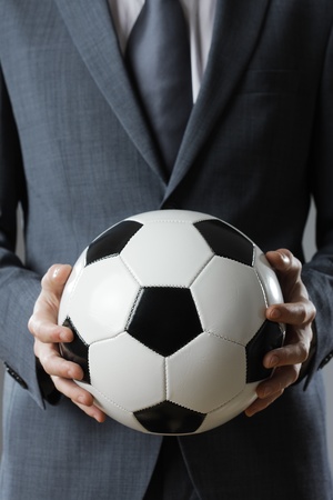 Elegant businessman holding a soccer ball, close upの写真素材