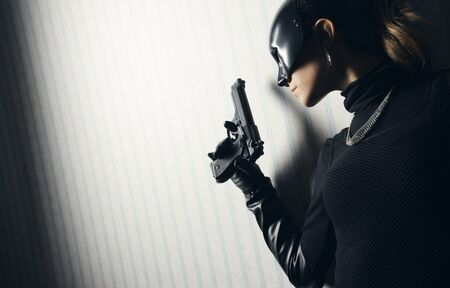 Female thief in black mask with gunの写真素材