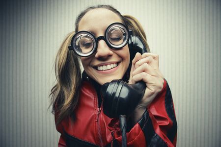 funny nerd humor woman talking retro vintage black telephone on vintage wallpaperの写真素材