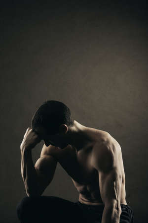 Bodybuilder concentrating on dark backgroundの写真素材