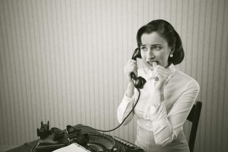 Woman embarrassed talking on phone at her desk
