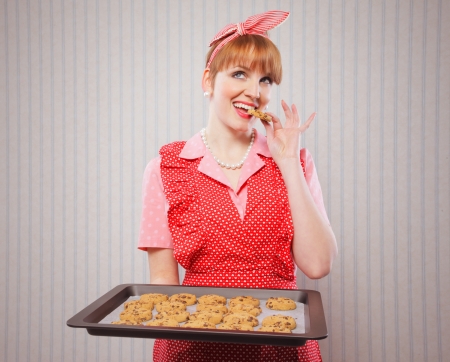 Retro housewife holding cookie tray full of chocolate cookie の写真素材