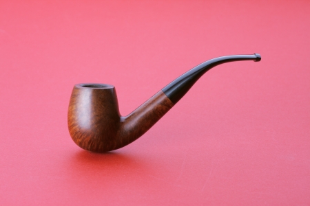 Tobacco pipe on red background, close up