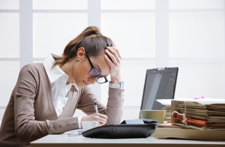 Young tired businesswoman with tons of documentsの写真素材