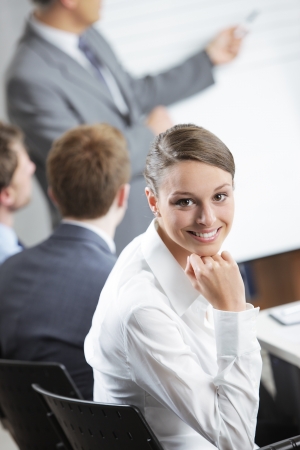 Portrait of a pretty young businesswoman smiling in a meeting with her colleagues in backgroundの写真素材
