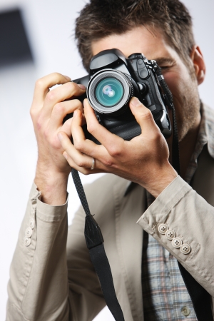 Young man taking photo with professional digital camera, focus on hand and lensの写真素材