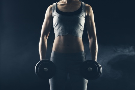 Fitness woman with weights on dark background