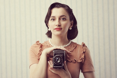Beautiful young woman with a old camera