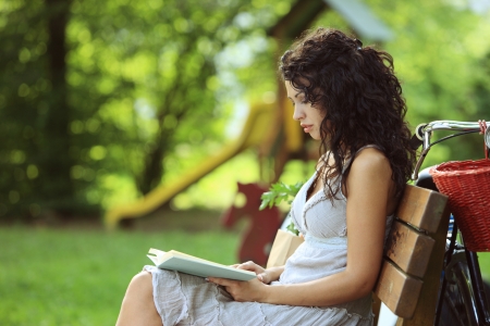 Young beautiful woman reading a book at a parkの写真素材