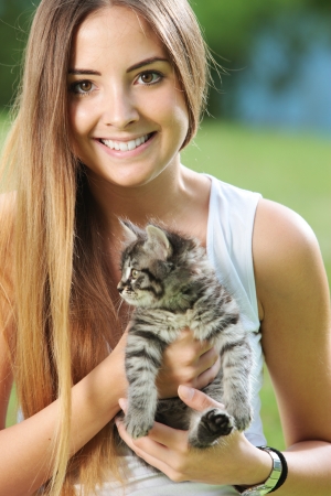 Smiling young woman playing outdoors with her kittyの写真素材
