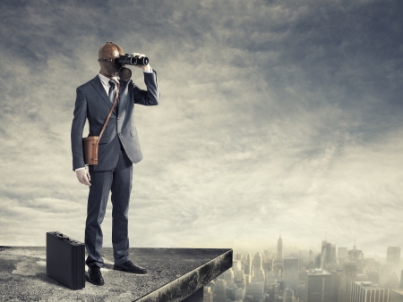 Businessman with gas mask looking through binoculars with a polluted city の写真素材