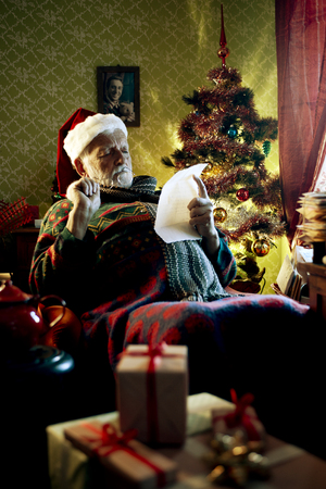 Portrait of Father Christmas sitting in armchair reading lettersの写真素材