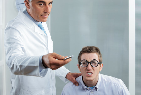 Optometrist pointing at eye chart, a nerd patient having difficultyの写真素材
