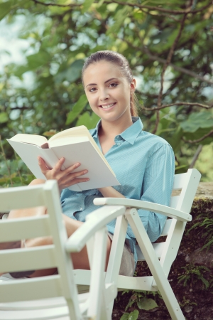 Beautiful girl reading a book outdoors enjoying a summer dayの写真素材