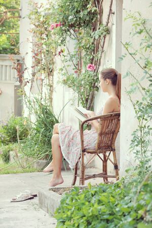Beautiful girl reading a book outdoors enjoying a summer dayの写真素材