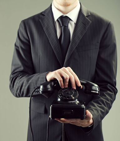 Elegant businessman holding an old black telephoneの写真素材