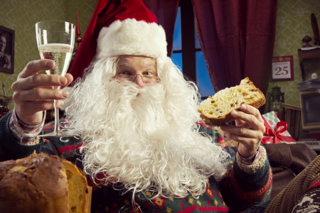 Portrait of Santa Claus celebrating with a glass of champagne and panettoneの写真素材